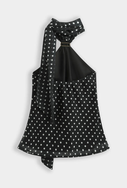 Top noir à pois blanc col foulard orné d’une broche dorée