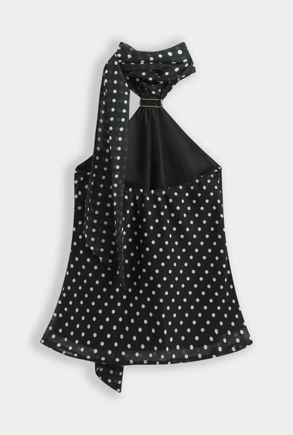 Top noir à pois blanc col foulard orné d’une broche dorée