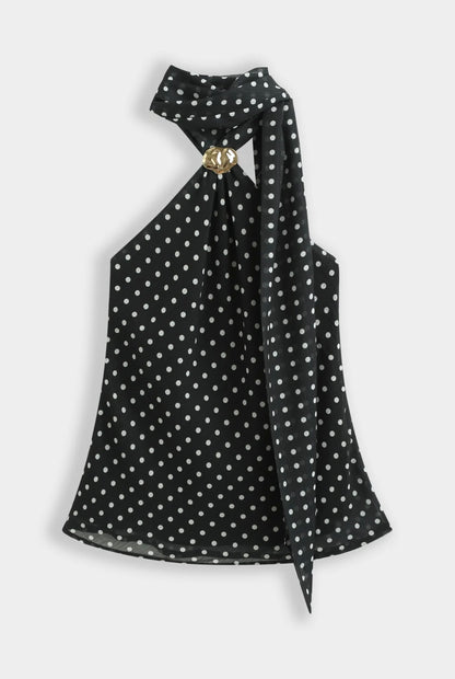 Top noir à pois blanc col foulard orné d’une broche dorée